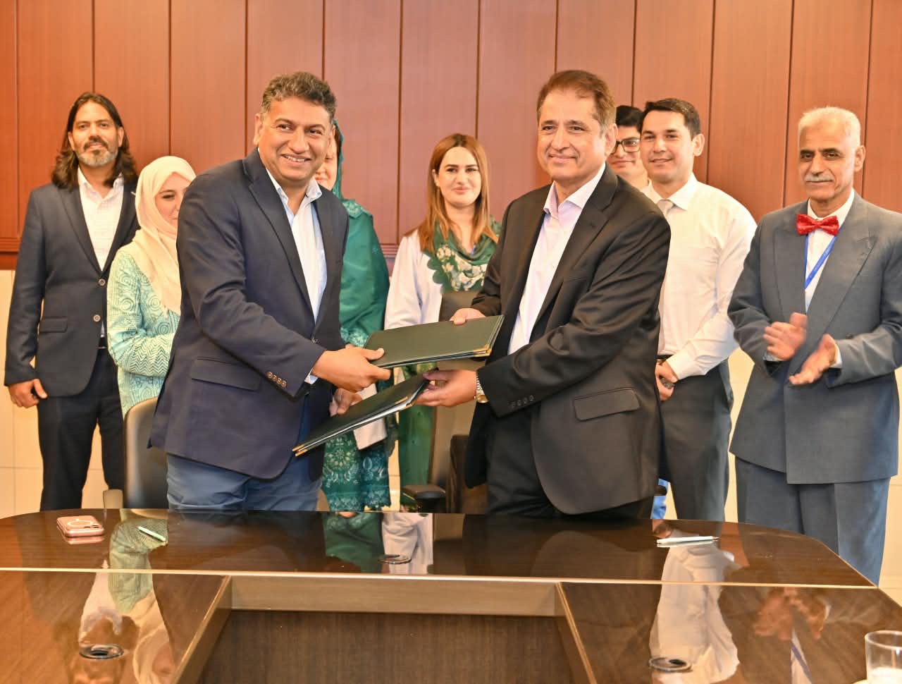 Dr. Faisal Habib Cheema and Prof. Syed Shahkar Ahmed Shah exchange signed MOU documents at Peshawar Institute of Cardiology